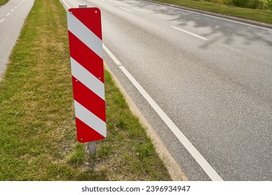 Red and white striped traffic sign on road as safety warning in summer