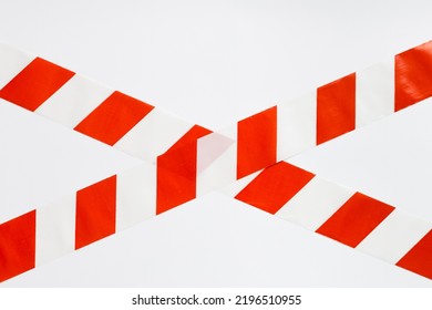 Red with white stripes signal tape in the shape of a cross, forbidding passage. White background, space for text.