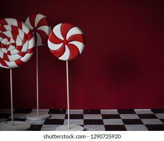 red and white stripped candies on red background.  lollipop standing on chessboard. copy space