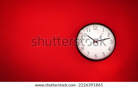red white wall clock hanging on a wall a simple flat lay image of a plastic wall clock over a red turquiose background with copy space and a central element.                      