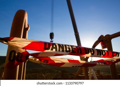 Red And White Warning Danger Tag Tape Sign Applying Taping Off Working Area Dropped Object With Defocused Crane Lifting High Risk Work Exclusion Droped Zone Construction Site, Perth City Australia  