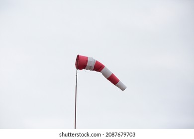 Red and white weather vane on a cloudy background