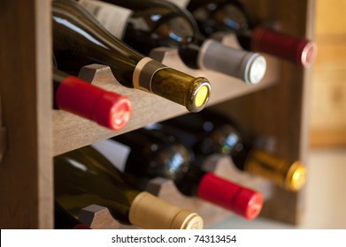 Red and white wine bottles stacked on wooden racks shot with limited depth of field