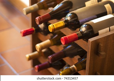 Red and white wine bottles stacked on wooden racks shot with limited depth of field