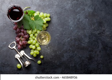 Red And White Wine Glasses And Grape Over Stone Table. Top View With Copy Space