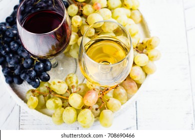 Red and white wine in glasses with grapes on white background. Assortment of autumn harvest beverages. Copy space