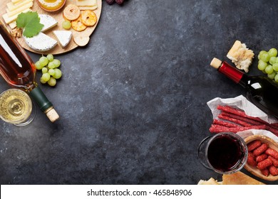 Red And White Wine, Grape, Honey, Cheese And Sausages Over Stone Table. Top View With Copy Space