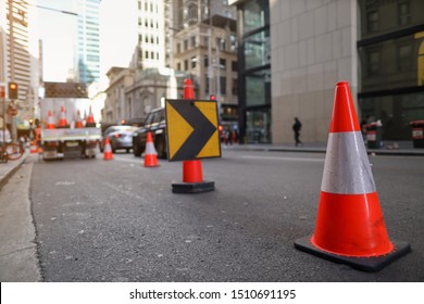 Red and white witches hat cone traffic warning sign barrier applying on busy street downtown on pedestrian footpath, road under construction defocused traffic controller Sydney city CBD, Australia 