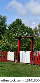 Red And White, Wooden Picket Fence Surrounded The Uptown Community Garden In Memphis, Tennessee.  Sunflowers Can Be Seen Blooming Behind Fence.