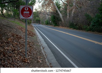 Red Wildfire Evacuation Route Sign With Ahead Arrow That Point In The Correct Direction Of Voluntary Or Mandatory Egress On Two-way Rural Road In California