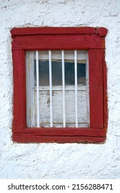 A red window and white wall of an aged building in northern Spain