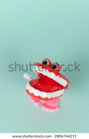 Red Wind-Up Chattering Teeth Toy on Aqua Background: Vintage Humor and Whimsy in Stock Photography