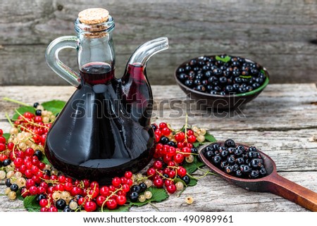 Red wine bottle and berries. Seasonal homemade alcohol in vintage decanter in wooden pantry