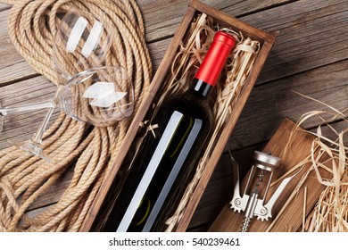 Red Wine Bottle In Box And Glasses On Wooden Table. Top View 