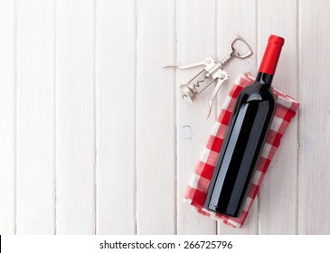 Red Wine Bottle And Corkscrew On White Wooden Table Background With Copy Space