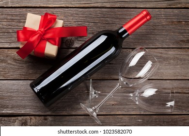 Red Wine Bottle And Gift Box On Wooden Table. Valentine's Day Greeting Card. Top View