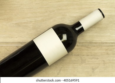 Red Wine Bottle Is Laying Down At The Light Wooden Background Closeup Empty Labels Attached