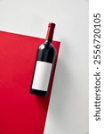 Red wine bottle mockup with white label placed against red and white background. Negative space for to insert text, brand name. Concept of drink and food, alcohol beverage.