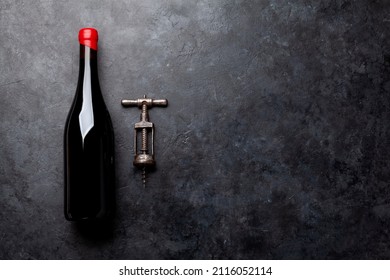 Red Wine Bottle And Vintage Corkscrew On Stone Table. Top View Flat Lay With Copy Space