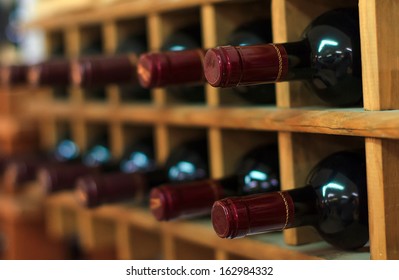 Red Wine Bottles Stacked On Wooden Racks