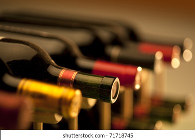 Red wine bottles stacked on wooden racks shot with limited depth of field