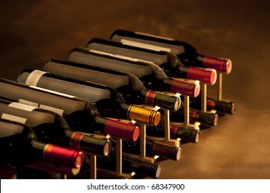 Red Wine Bottles Stacked In Rack On Warm Background