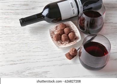 Red wine and chocolate truffles on white wooden table