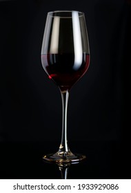 Red Wine In A Clear Glass Glass With Highlights. Black Background With Reflection