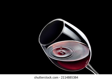 red wine drop falling in glass and created splash with circle ripple isolated on black background