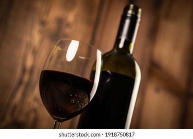 Red wine glass and bottle red wine on old wooden background. 
