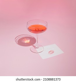 Red Wine Glass And Romantic Card With Lipstick Kiss On Pastel Pink Background. Trendy And Minimal Valentine's Day Aesthetic.