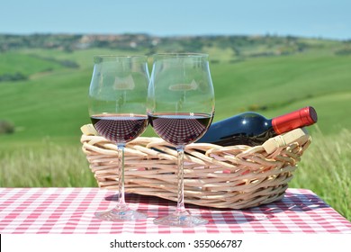 Red wine on the checkered cloth against Tuscan landscape. Italy