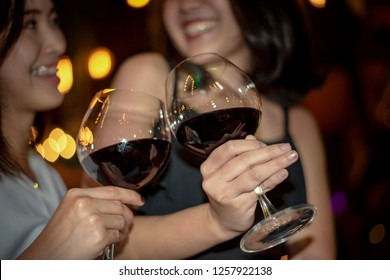 Red Wine Party. Romantic Lesbian Gay Couple Enjoying Dinner At Home, Love, Relationship, Romantic Concept. Happy Celebrating And Making Cheers With Glasses Of Red Wine Against Blurred Bokeh Night Club