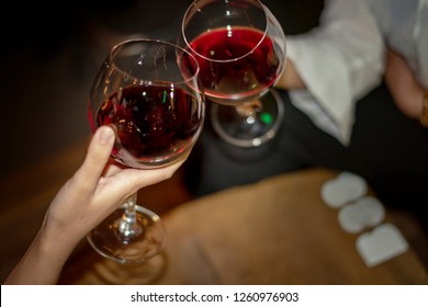 Red Wine Party. Romantic Lesbian Gay Couple Enjoying Dinner At Home, Love, Relationship, Romantic Concept. Happy Celebrating And Making Cheers With Glasses Of Red Wine Against Blurred Bokeh Night Club