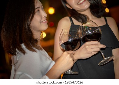 Red Wine Party. Romantic Lesbian Gay Couple Enjoying Dinner At Home, Love, Relationship, Romantic Concept. Happy Celebrating And Making Cheers With Glasses Of Red Wine Against Blurred Bokeh Night Club