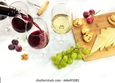 Red Wine Poured Into A Glass With Dispenser At A Tasting, With Cheese, Bread, And Grapes. Selective Focus