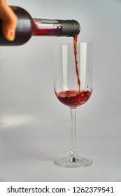Red wine poured into slim wine glass              