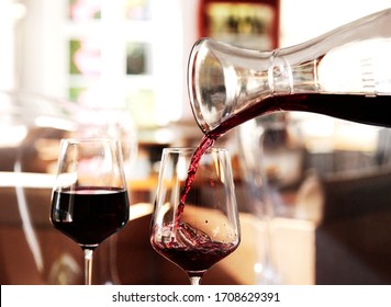 Red wine pouring from a decanter into a glass