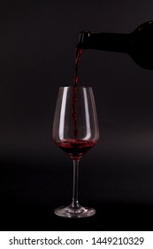 Red Wine Pouring In The Glass On The Black Background