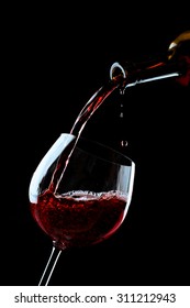 Red Wine Pouring Into Wine Glass On Black Background