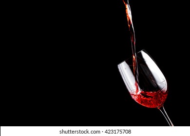 Red Wine Pouring Into A Wine Glass. Isolated On Black Background. 