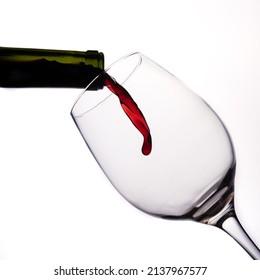 Red wine pouring on white background before falling into the glass