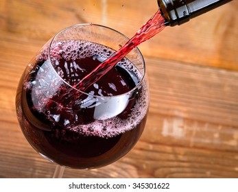 Red Wine Pouring On Wood, Close Up