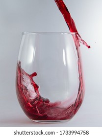 Red Wine Pouring And Spilling Over The Edge Of A Stemless Glass