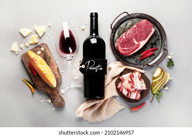 Red wine Primitivo with appetizers on gray background. Traditional alcohol drinks. Top view, flat lay, copy space
