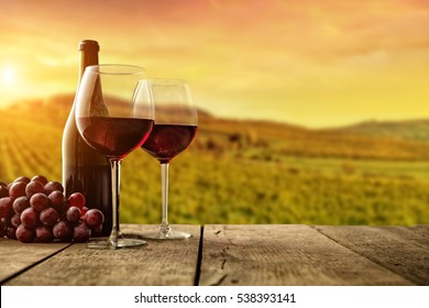Red wine served on wooden planks, vineyard on background, copyspace for text