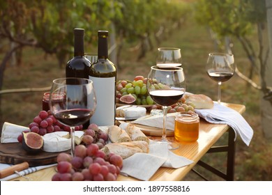 Red Wine And Snacks Served For Picnic On Wooden Table Outdoors