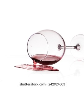 Red wine spilled from glass over white background