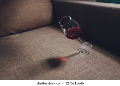 Red wine spilled on a grey couch sofa.