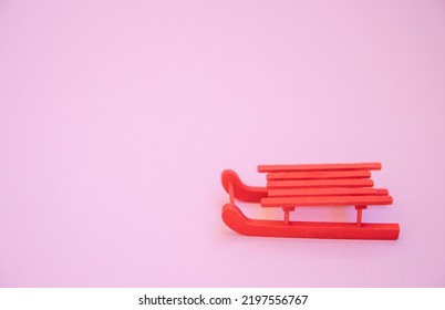 Red Winter Sled On A Pink Background, The Concept Of Winter And New Year Holidays, Empty Space For Text.
